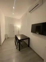 Interior Apartment living room with dark dining table, wall-mounted flat-screen TV and air conditioning unit